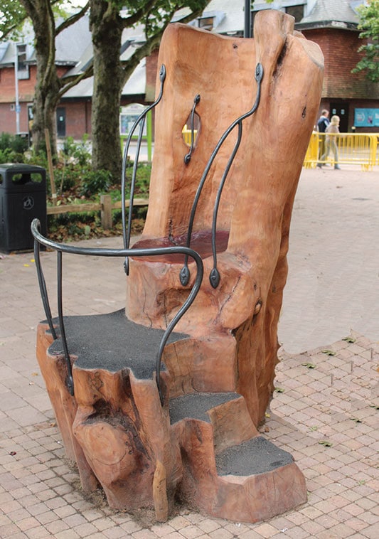 Tree trunk carved into throne seat with metal handrail